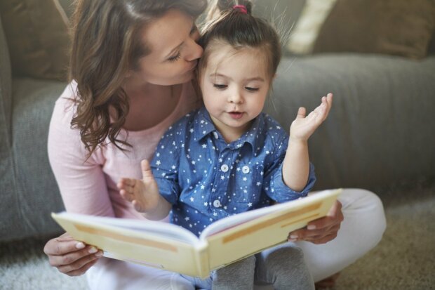 Eine Mutter liest ihrer kleinen Tochter ein Buch vor