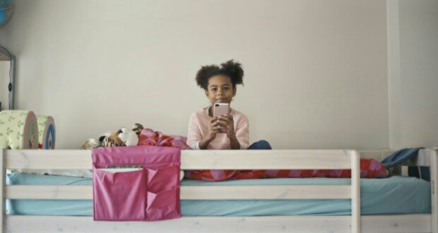 Mädchen sitzt mit Smartphone im Bett. Die Displayzeit sollte nicht nach Stunden begrenzt sein, sondern klar, für alle einhaltbare regeln verfolgen. Bild: bruce-mars-p4e4y4J7H4k-unsplash