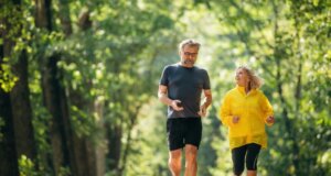 Zwei Menschen über 50 beim Joggen in schöner grüner Umgebung. Gesundheitsvorsorge ab 50 ist wichtig. Bild: iStock-2180466138-standret