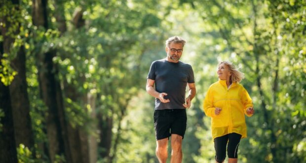 Zwei Menschen über 50 beim Joggen in schöner grüner Umgebung. Gesundheitsvorsorge ab 50 ist wichtig. Bild: iStock-2180466138-standret
