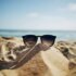 Sonnenbrille im Sand. Urlaub geht auch nachhaltig. Tipps dafür gibt's im Text.